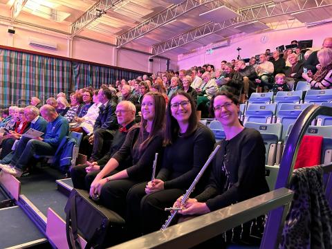 Members of the flute section sitting with the audience